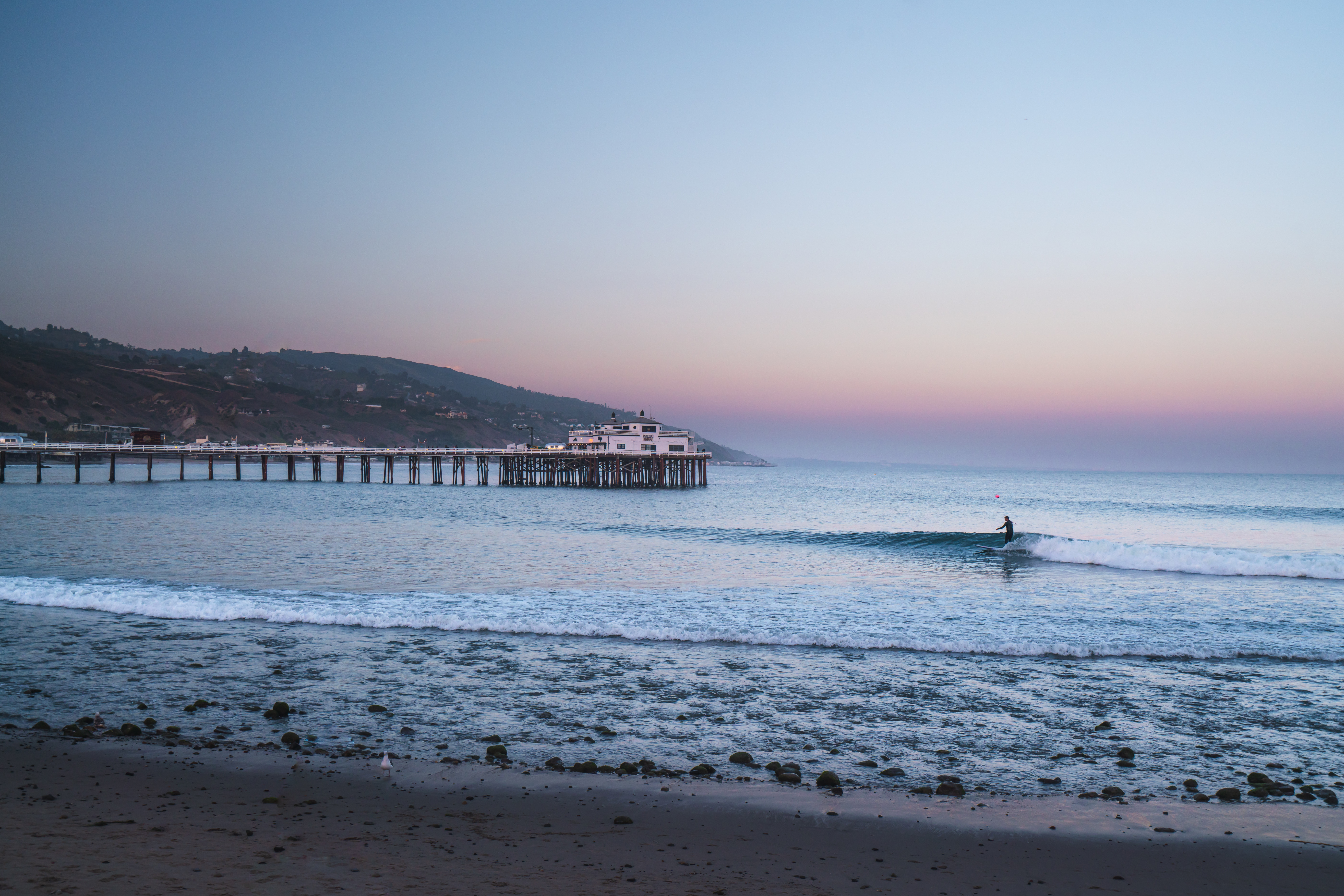 sunset and surfer at the malibu pier california